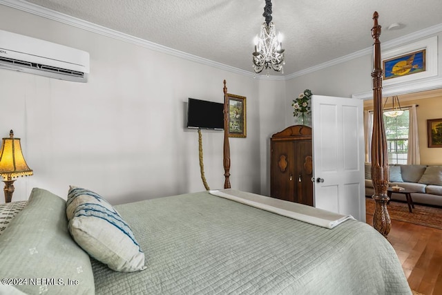 bedroom with a wall mounted AC, a textured ceiling, wood finished floors, crown molding, and a chandelier