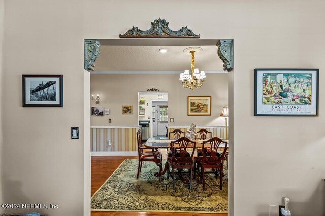 dining area featuring wood-type flooring, an inviting chandelier, and ornamental molding