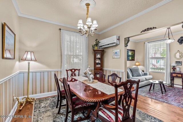 dining area with a wall mounted AC, crown molding, a textured ceiling, a chandelier, and wood-type flooring