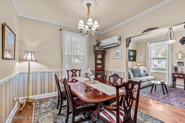 dining room with a chandelier, a wainscoted wall, an AC wall unit, and wood finished floors