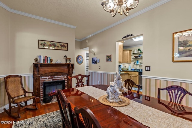 dining space with wood finished floors, an inviting chandelier, ornamental molding, wainscoting, and a brick fireplace
