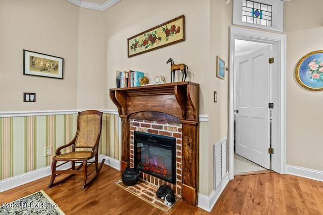 sitting room featuring visible vents, baseboards, a brick fireplace, and wood finished floors