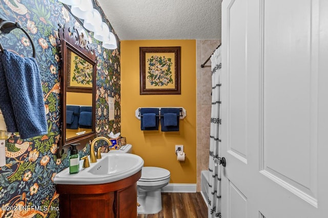 full bathroom featuring vanity, wood finished floors, baseboards, a textured ceiling, and toilet
