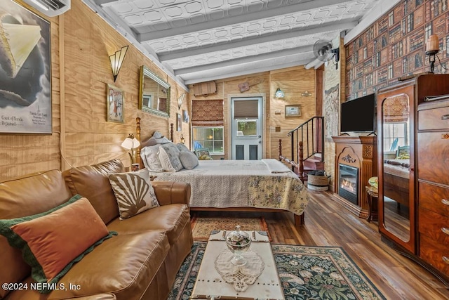 bedroom with beamed ceiling, a wall mounted air conditioner, wooden walls, and wood finished floors