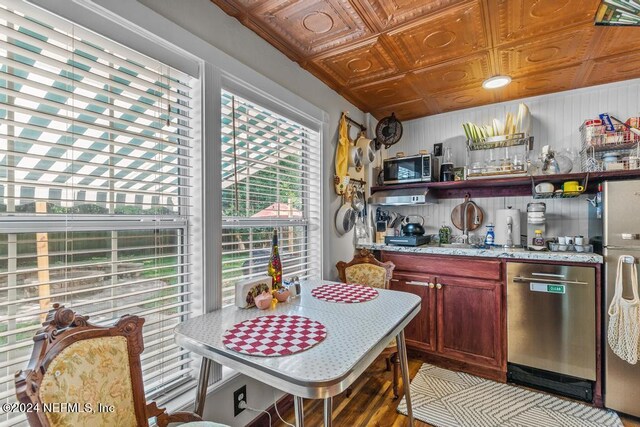 kitchen with dishwasher, light stone counters, and hardwood / wood-style flooring