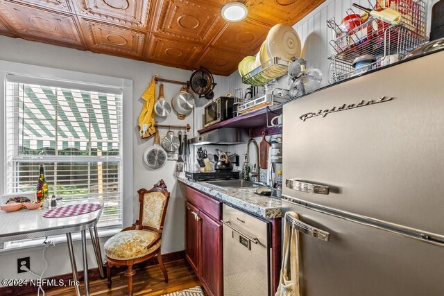 kitchen featuring light stone countertops, plenty of natural light, stainless steel appliances, and sink