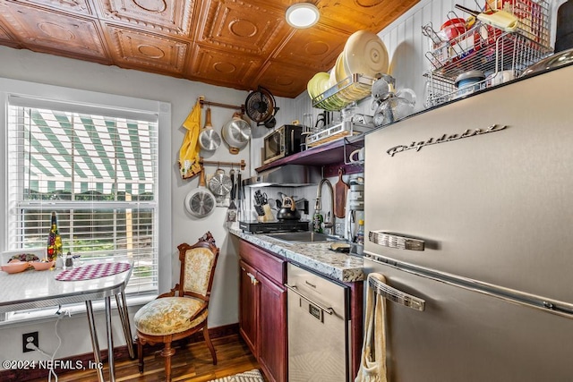 kitchen with a sink, open shelves, wood finished floors, appliances with stainless steel finishes, and baseboards