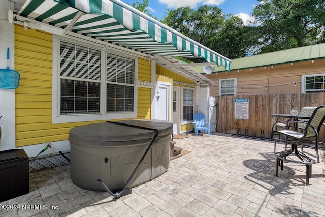 view of patio with a hot tub and fence