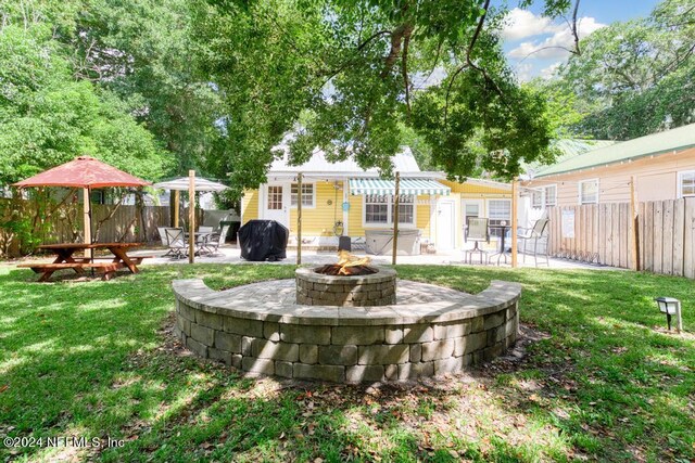 rear view of property with an outbuilding, a lawn, a patio, and an outdoor fire pit