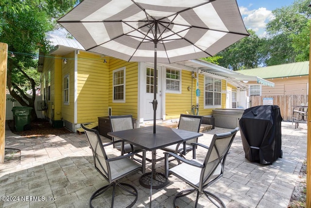 view of patio / terrace featuring area for grilling, outdoor dining area, and a hot tub