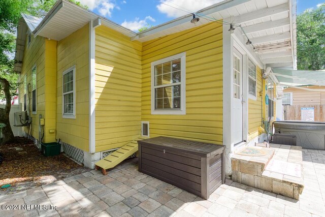 rear view of property featuring a patio and a hot tub