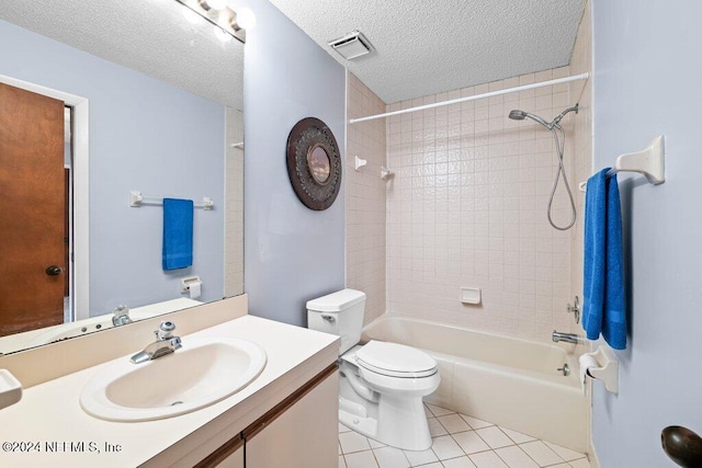 full bathroom with tile patterned flooring, vanity, tiled shower / bath combo, toilet, and a textured ceiling