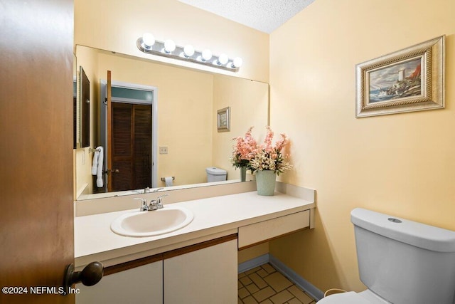 bathroom with vanity, a textured ceiling, and toilet