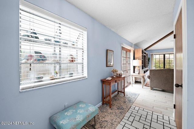 hallway featuring vaulted ceiling and a textured ceiling