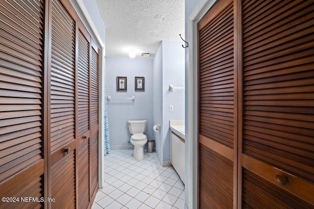 bathroom featuring tile patterned flooring, vanity, a textured ceiling, and toilet