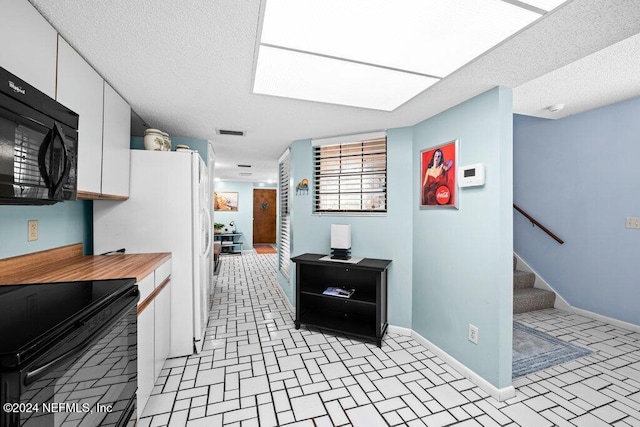 kitchen featuring white cabinets, a textured ceiling, and black appliances