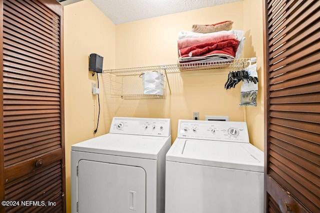 clothes washing area with washer and dryer and a textured ceiling