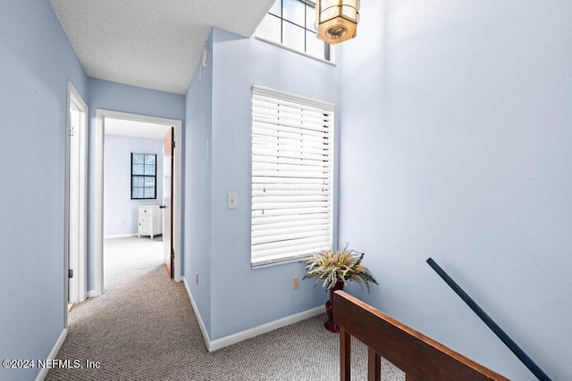 hall with carpet floors and a textured ceiling