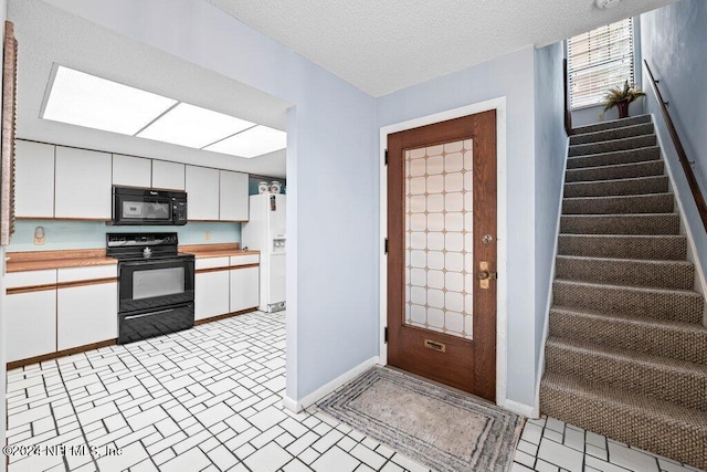 kitchen featuring a skylight, white cabinets, a textured ceiling, and black appliances