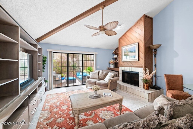 living room with a tile fireplace, lofted ceiling, ceiling fan, a textured ceiling, and light hardwood / wood-style flooring