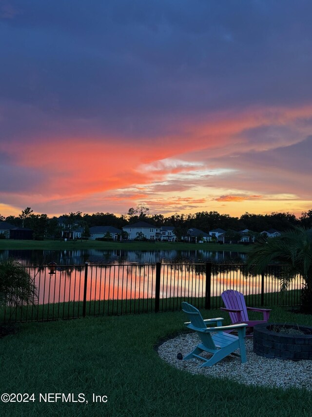 yard at dusk featuring an outdoor fire pit and a water view