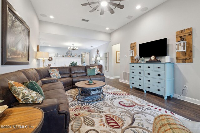 living room featuring ceiling fan with notable chandelier and dark wood-type flooring