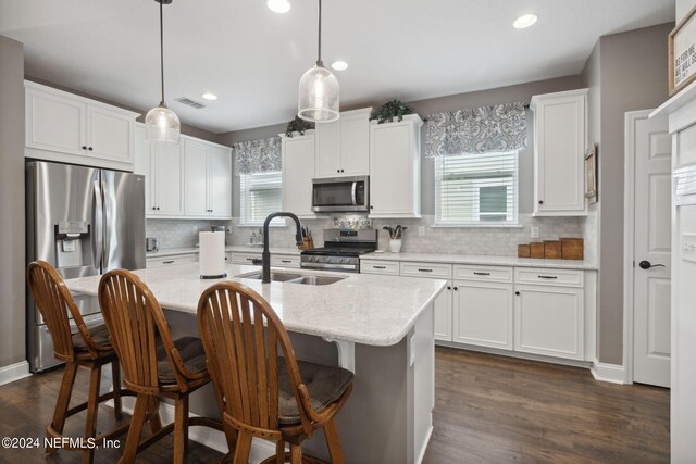 kitchen with appliances with stainless steel finishes, pendant lighting, and dark hardwood / wood-style floors