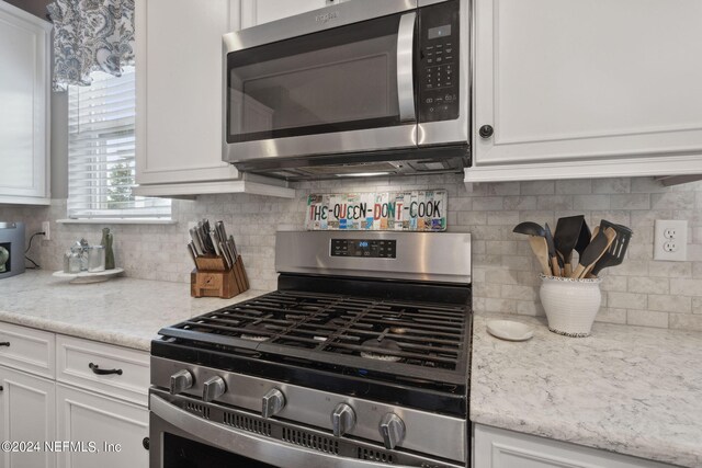 kitchen featuring white cabinets, light stone counters, stainless steel appliances, and decorative backsplash