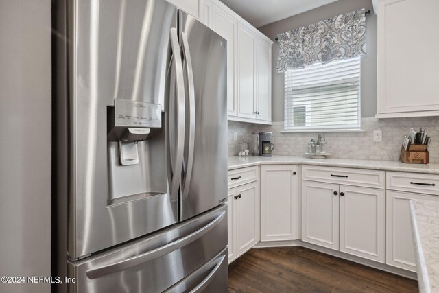 kitchen with light stone countertops, white cabinetry, dark hardwood / wood-style floors, stainless steel fridge with ice dispenser, and tasteful backsplash