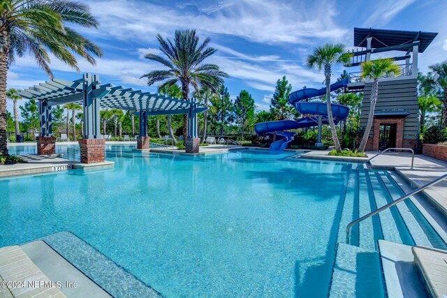 view of pool featuring a water slide, a pergola, and a patio area