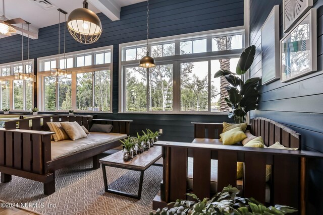 sunroom / solarium featuring ceiling fan, beam ceiling, and a healthy amount of sunlight