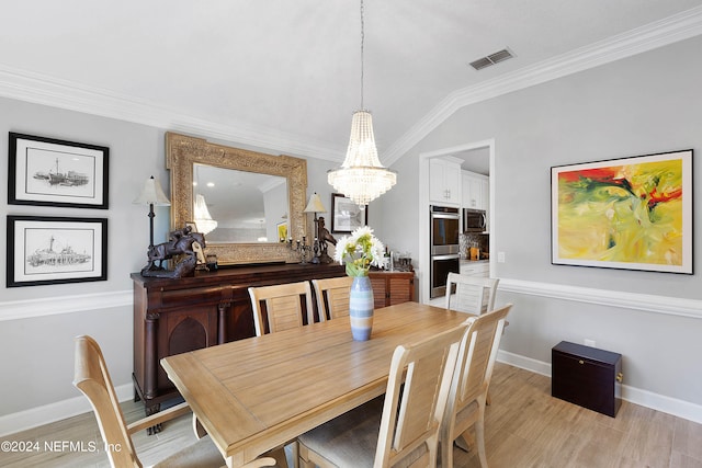 dining room with light wood-type flooring, ornamental molding, a chandelier, and lofted ceiling