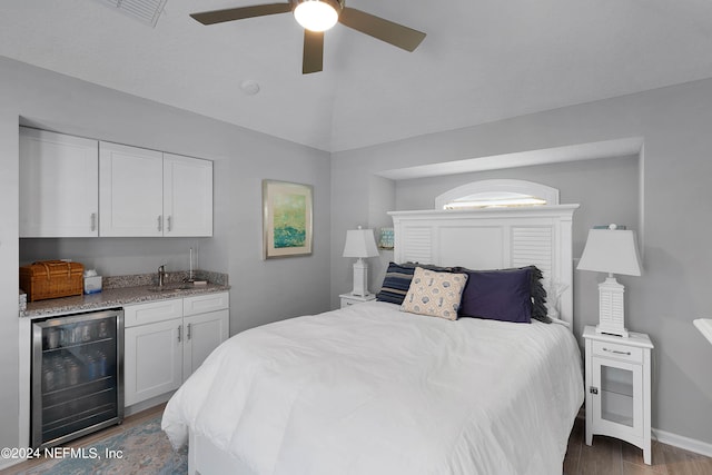 bedroom featuring wine cooler, wet bar, wood-type flooring, ceiling fan, and vaulted ceiling