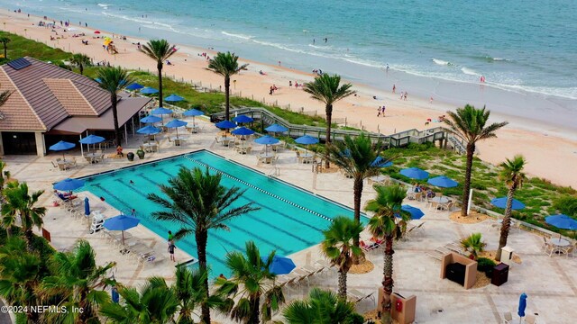 view of pool featuring a patio area, a view of the beach, and a water view