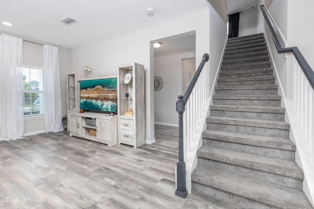 stairway with visible vents, baseboards, and wood finished floors