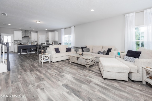 living room featuring recessed lighting, wood finished floors, visible vents, and a textured ceiling