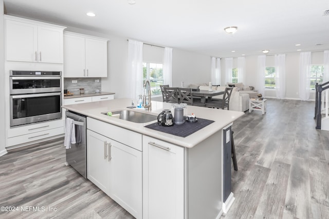 kitchen with open floor plan, a center island with sink, light countertops, appliances with stainless steel finishes, and a sink