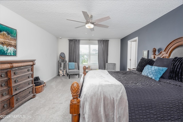 bedroom with baseboards, light colored carpet, a textured ceiling, and a ceiling fan