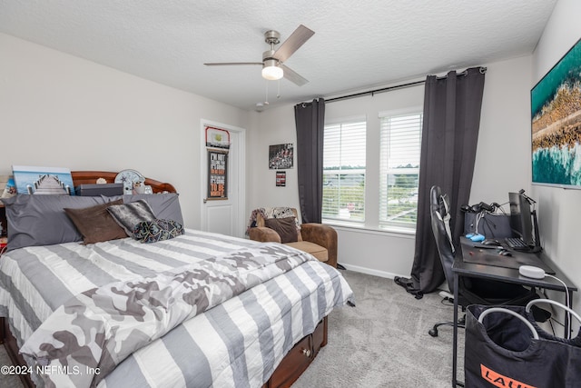 bedroom with a textured ceiling, ceiling fan, baseboards, and light carpet