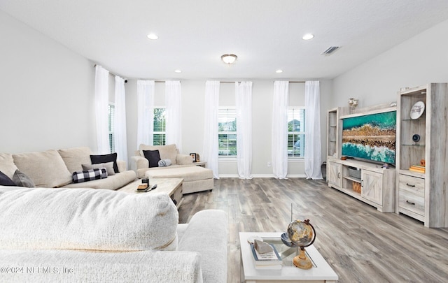 living room with recessed lighting, wood finished floors, visible vents, and baseboards