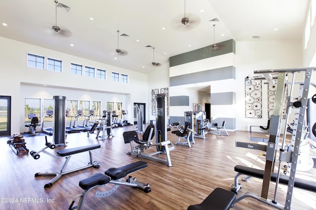 workout area featuring wood finished floors, visible vents, and a towering ceiling