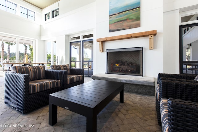 living area with brick floor, a high ceiling, a healthy amount of sunlight, and a fireplace with raised hearth