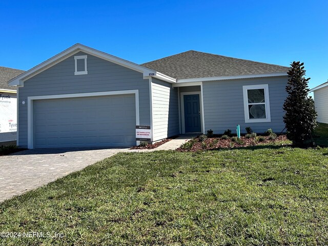 ranch-style home with an attached garage, a front lawn, decorative driveway, and roof with shingles