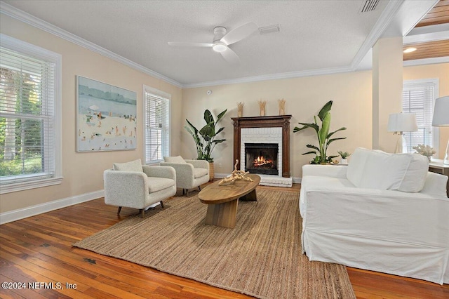 living room with a fireplace, ceiling fan, crown molding, and wood-type flooring