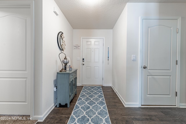 doorway featuring a textured ceiling, dark wood-type flooring, and baseboards