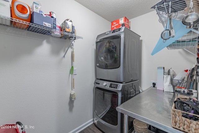 washroom with laundry area, baseboards, wood finished floors, a textured ceiling, and stacked washing maching and dryer