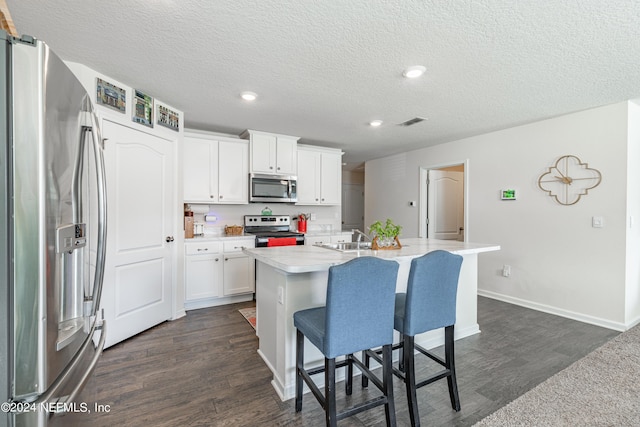 kitchen featuring light countertops, visible vents, appliances with stainless steel finishes, a sink, and a kitchen bar