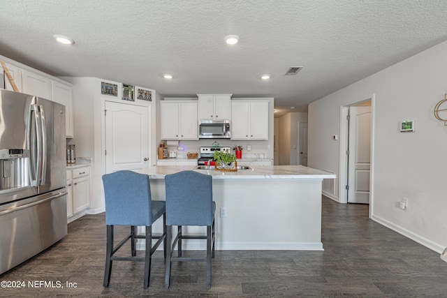 kitchen featuring a kitchen island with sink, stainless steel appliances, and white cabinetry