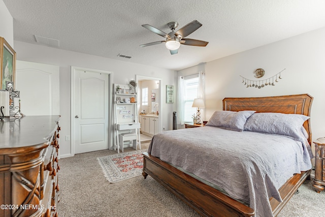 carpeted bedroom featuring visible vents, ceiling fan, a textured ceiling, and ensuite bath