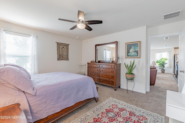 bedroom with stainless steel refrigerator with ice dispenser, visible vents, light carpet, and baseboards